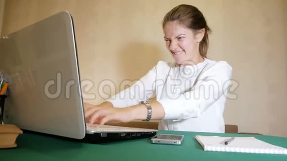 年轻女子很快就在笔记本电脑上打字面部表情像疯了一样自由职业者的繁重工作视频的预览图