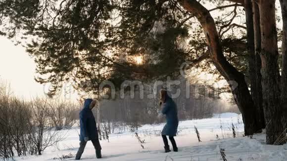 男人和女人在冬天的森林里打雪球冬天森林的日落视频的预览图