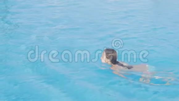 穿白色比基尼的年轻女孩在游泳池里游泳在室外的水中少女在阳光明媚的日子里享受暑假视频的预览图