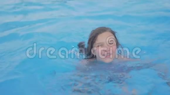 小女孩在游泳池里游泳青少年女孩在室外游泳池的水中享受阳光明媚的暑假视频的预览图