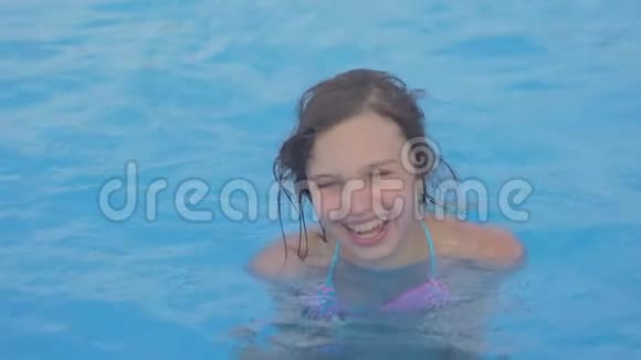 小女孩在游泳池里游泳青少年女孩在室外游泳池的水中享受阳光明媚的暑假视频的预览图