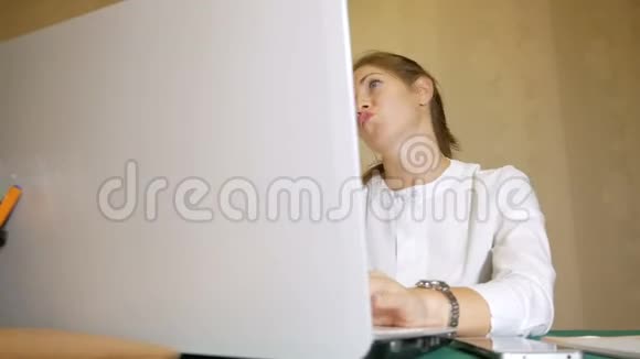 一个穿着白色衬衫的女孩在笔记本电脑上打字简直疯了长期工作的后果视频的预览图