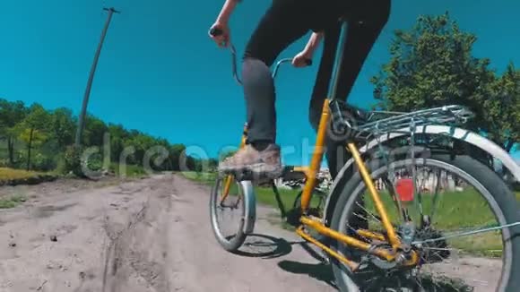 年轻女子骑着老式自行车沿着一个村庄的农村道路动作缓慢视频的预览图