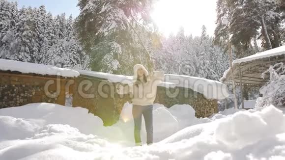 穿着针织毛衣和毛皮帽的漂亮女孩在Chalet附近享受阳光明媚的冬日视频的预览图