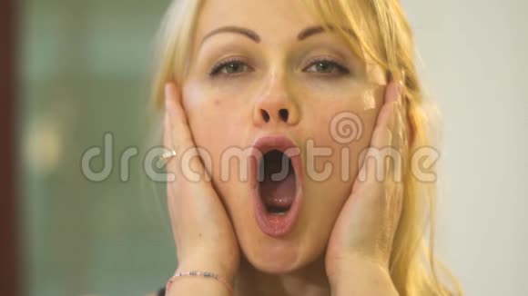 一个张开嘴的女人抓住她的脸颊伸展她的嘴唇视频的预览图