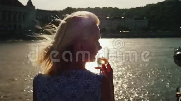 在多瑙河上享受河游一位手里拿着玻璃杯的妇女看着布达佩斯的海岸线视频的预览图