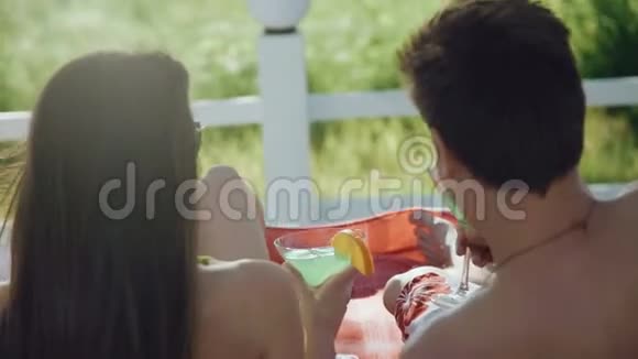 在海滩上休息的情侣的后景用鸡尾酒碰杯视频的预览图