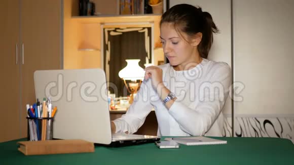 穿着白色衬衫的女孩在笔记本电脑后面的家里工作记者看着屏幕非常紧张视频的预览图