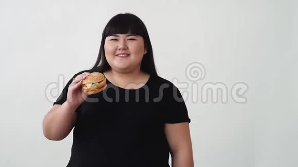 亚洲外表的女孩吃汉堡享受味道年轻人的饮食不健康视频的预览图