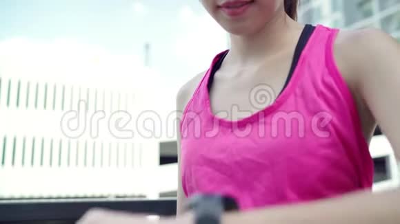 健康美丽的年轻亚洲运动员妇女设置和检查进展看心率监测在智能手表运行视频的预览图