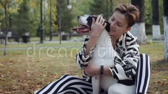 女人坐在地上拥抱她的斯塔福德狗视频的预览图