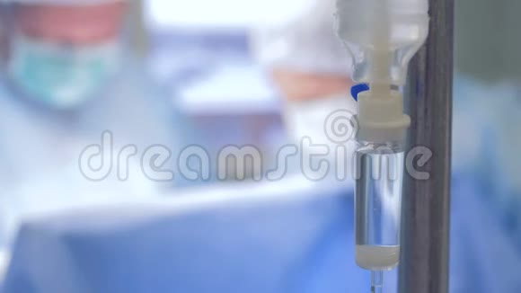 关闭一个完整的滴瓶与一组外科医生在后台工作视频的预览图