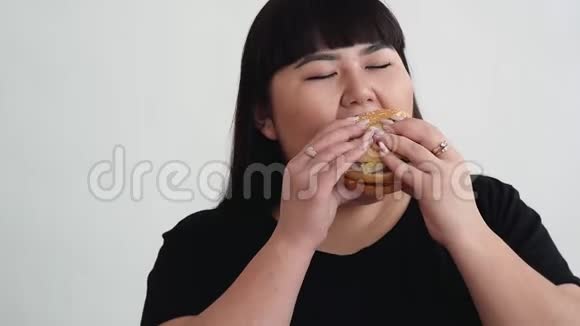 亚洲外表的女孩吃汉堡享受味道年轻人的饮食不健康视频的预览图