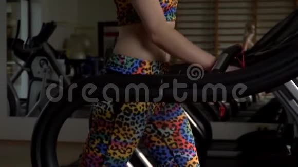 健身房里的一个女孩在跑步机上行走时感到温暖视频的预览图