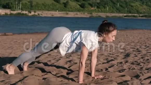 女人在城市河边的海滩上伸展瑜伽美丽的景色文尼亚萨视频的预览图
