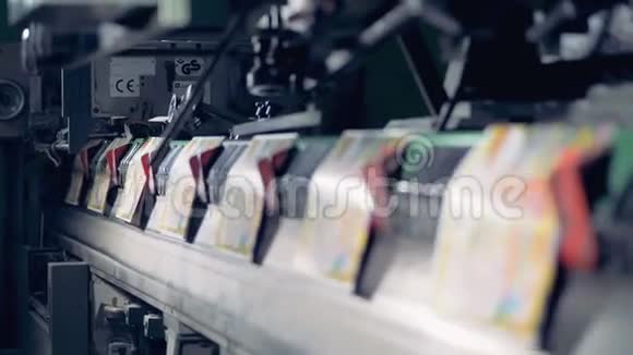 一排彩色印刷的纸正沿着工厂的传送带前进视频的预览图