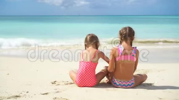 可爱的小女孩在海滩上玩沙子孩子们坐在浅水里做一个视频的预览图
