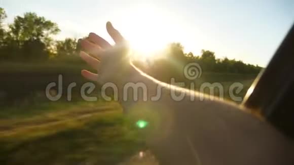 女孩从车窗上挥动她的手捕捉到美丽的阳光慢动作视频的预览图