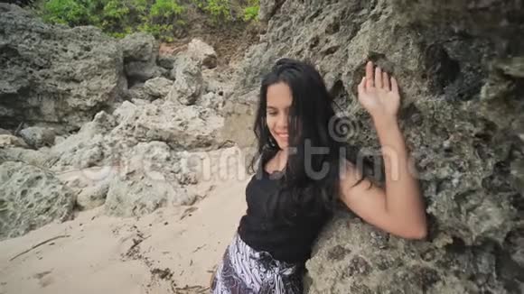 印度尼西亚女孩在巴厘岛美丽的岩石海滩上摆姿势伊多尼西亚视频的预览图