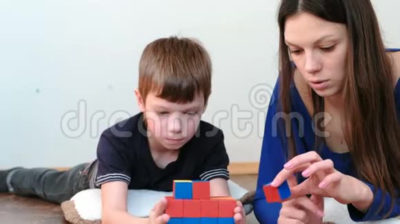 用积木和立方体建造塔楼妈妈和儿子一起玩着木制的彩色教育玩具积木视频的预览图
