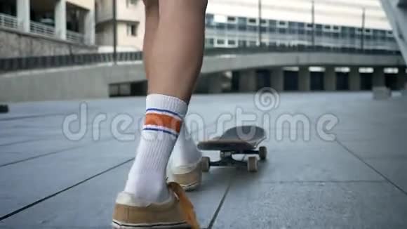 滑板运动员在城市滑冰时的双脚男子的双腿在滑板上玩把戏从后面可以看到视频的预览图