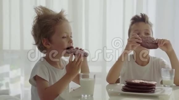 两个男孩在厨房吃自制的带牛奶的巧克力饼干视频的预览图