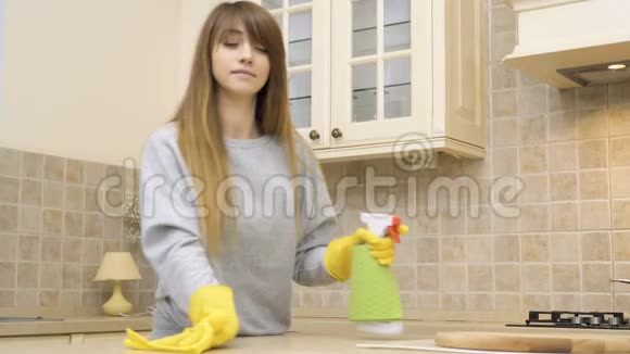 年轻漂亮的女孩用清洁剂清洁厨房桌子视频的预览图