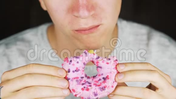 一个饥饿的年轻人吃甜甜圈的肖像视频的预览图
