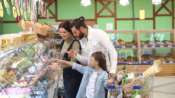 漂亮的父母和他们的女儿正在超市里选择糖果视频的预览图
