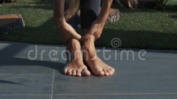 女孩在瑜伽姿势中弯曲身体赤脚脚踝视频的预览图