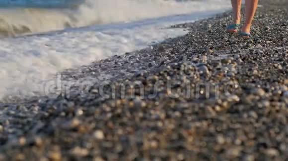 日落时分苗条女人腿在鹅卵石海岸上行走的特写镜头视频的预览图