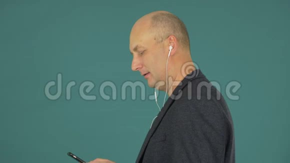 帅哥戴着耳机听音乐在绿色背景下跳舞侧视图视频的预览图