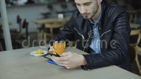 年轻帅哥在4K咖啡厅喝果汁用智能手机视频的预览图