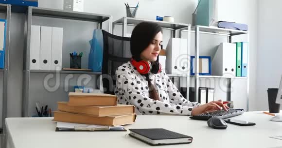 女人肩膀上戴着红色耳机拇指书和笔记本电脑视频的预览图