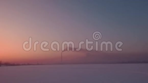 飞越雪域日落和孤独的烟囱茎与烟雾在地平线上视频的预览图