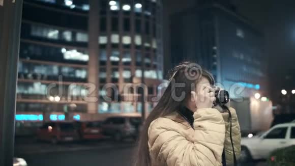 一位女摄影师用老式胶卷相机拍摄夜市视频的预览图
