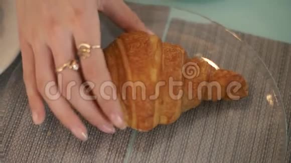 女用手从咖啡屋的桌上的玻璃盘子里拿出牛角面包视频的预览图