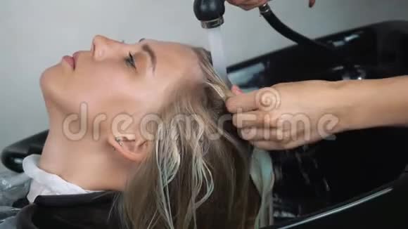 发型师用软管喷洒头发在美容院冲洗女顾客头发视频的预览图