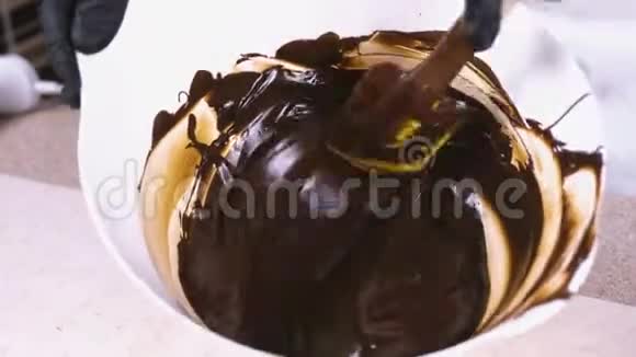 将液体黑巧克力与刮刀混合在白色碗中特写镜头视频的预览图