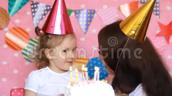 生日快乐母亲祝贺拥抱和亲吻她的孩子在聚会上吹灭蛋糕上的蜡烛粉色视频的预览图