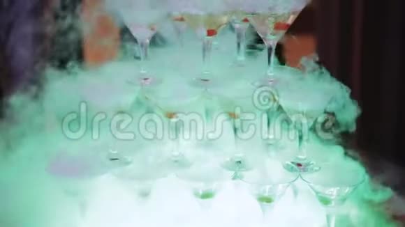 服务员把香槟倒入带有绿色樱桃和干冰蒸汽的玻璃杯中香槟滑梯金字塔或喷泉视频的预览图