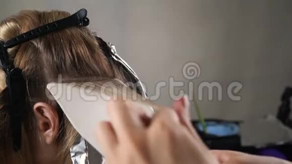 发型师做染发发烫她用刷子近景理发师他的手戴黑手套视频的预览图