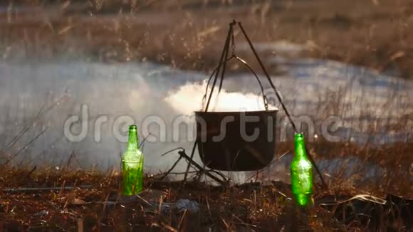 游客在篝火旁提供食物在远足中烹饪户外活动老水壶正烧在木桩上视频的预览图