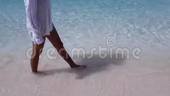 在蓝水沙滩上散步的女人视频的预览图