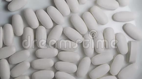 白色背景的医用药片和药丸关闭白色胶囊旋转在桌子上视频的预览图