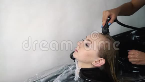 发型师用软管冲洗女性顾客沙龙的头发视频的预览图