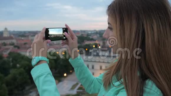 一个甜美的女孩一个观景台上的旅行者为城市拍照视频的预览图