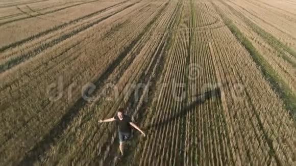 年轻成功的快乐男人在田野上奔跑手臂伸出空中全景视频的预览图