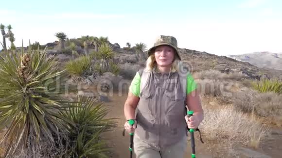 在莫哈韦沙漠的小径上徒步旅行的活跃成熟女性正前方视频的预览图
