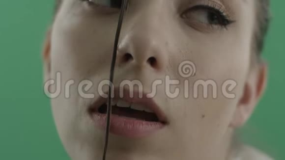 一个脸上沾着绿色背景的湿发的女人视频的预览图